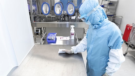 Cleanroom worker cleaning with sterile IPA wipe on hard surface.