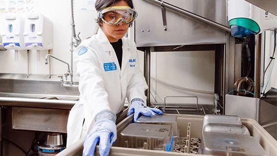 Person Holding Stack of Plates in Commercial Kitchen